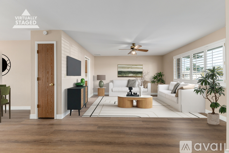 A living room with a white sofa, a wooden door, a black cabinet, and a ceiling fan.