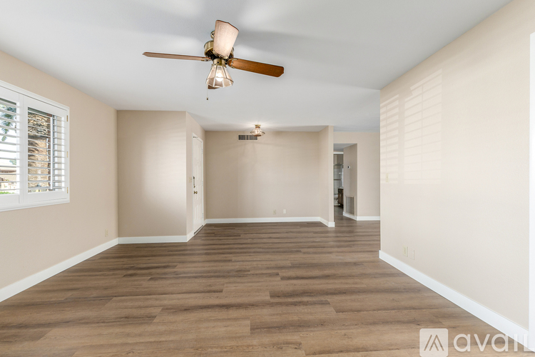 A spacious room with wooden flooring and a ceiling fan.