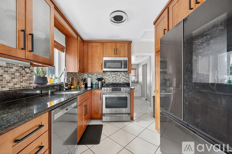 A kitchen with wooden cabinets and a black fridge.
