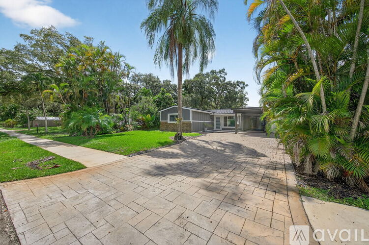 A house with a driveway surrounded by greenery and trees.