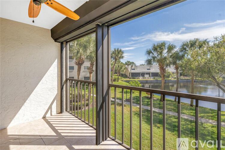 A balcony with a fan and a view of a lake and trees.