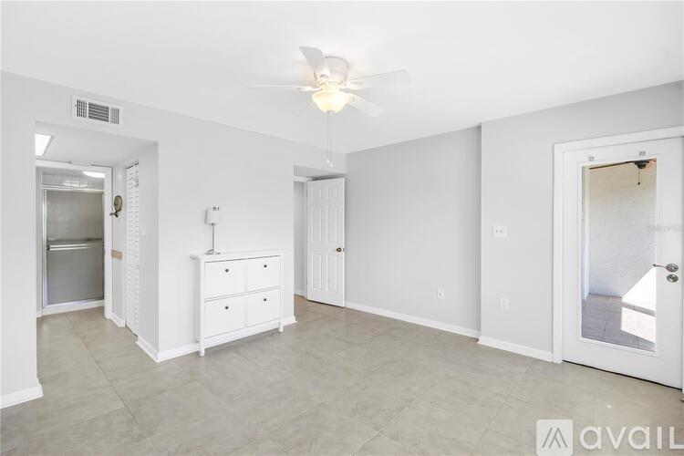 A white bedroom with a dresser and a ceiling fan.