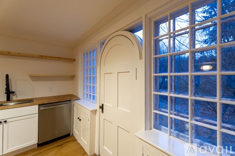 A kitchen with white cabinets and a window with a view of trees outside.