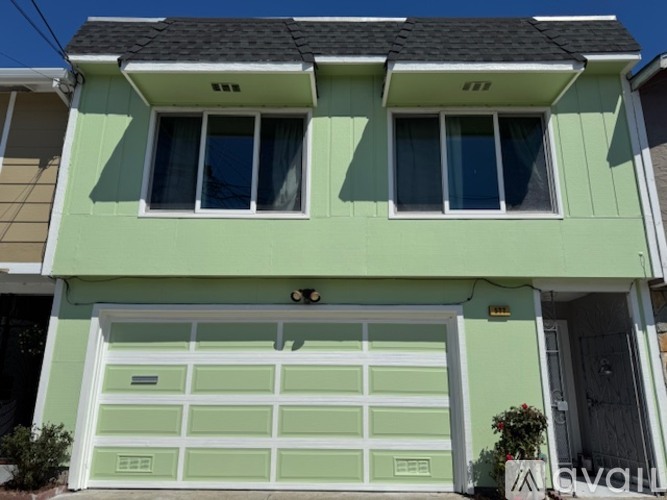 A two-story house with a green garage door.