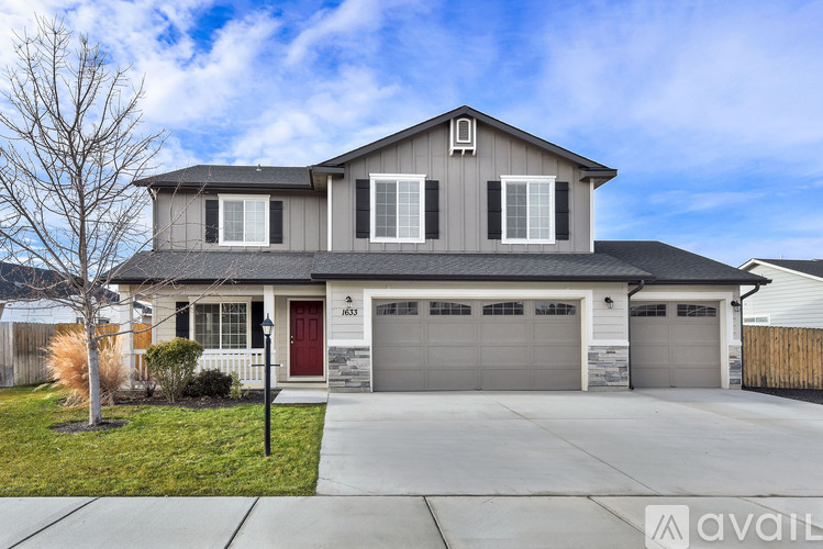 A two-story house with a red door and garage doors.