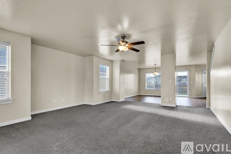 A spacious room with a ceiling fan and carpeted floor.