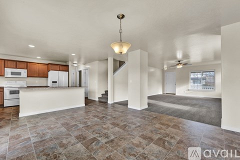 A large open living space with a kitchen area to the left and a staircase to the right.