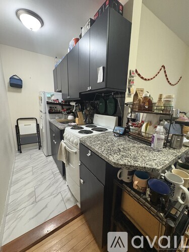 A kitchen with a granite counter top and a black fridge.