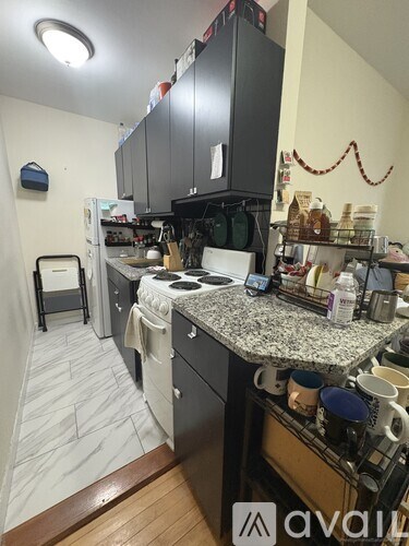 A kitchen with a granite counter top and a black fridge.