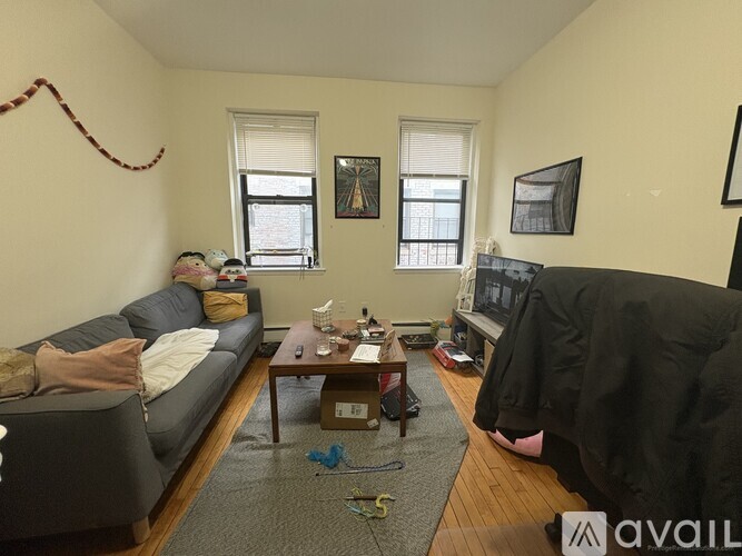 A living room with a grey couch, a coffee table, and a window.