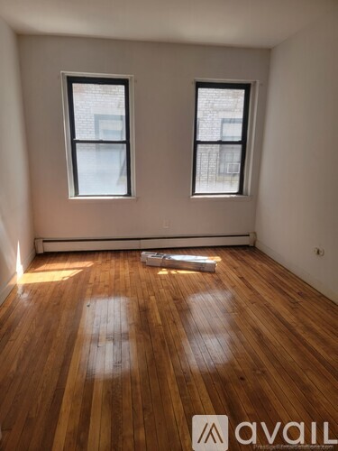 A room with wooden floors and two windows.