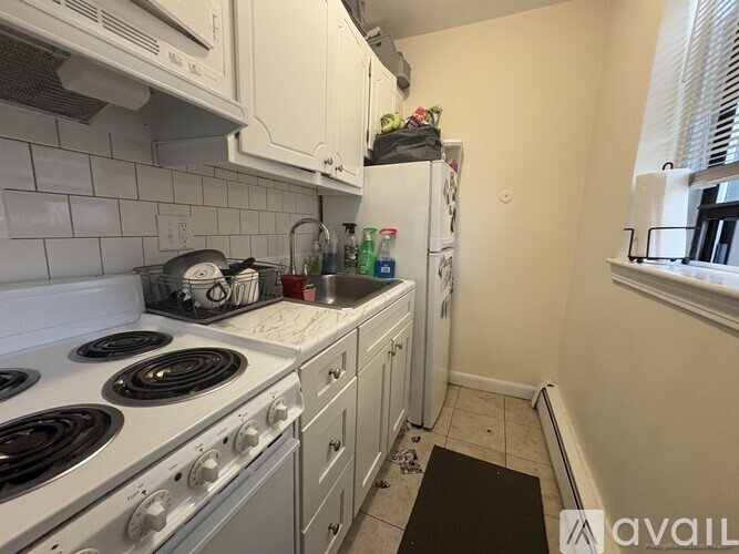 A kitchen with a white stove top oven and white cabinets.