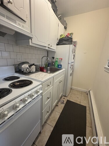 A kitchen with white appliances and a black mat on the floor.