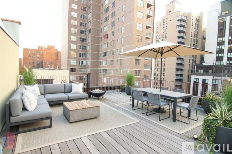 A patio with a table, chairs, and an umbrella is surrounded by buildings.
