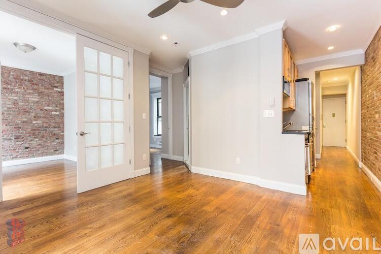A spacious room with wooden floors and a brick wall.