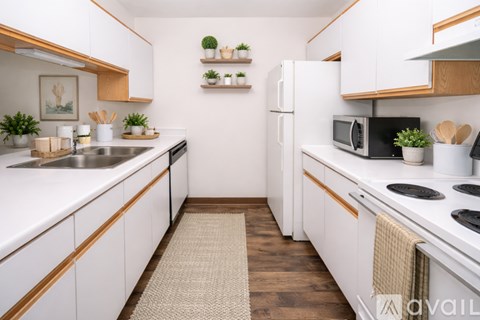 A kitchen with white cabinets and a beige rug on the floor.