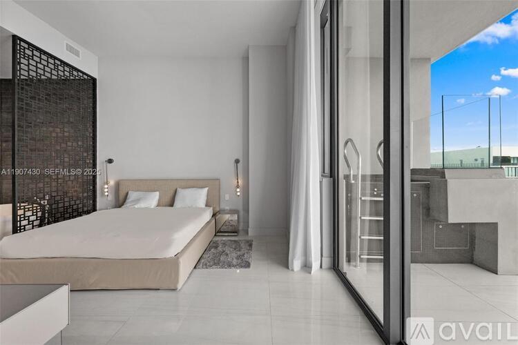 A bedroom with a large bed and a glass walled shower.