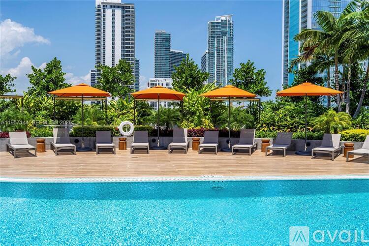 A pool area with chairs and umbrellas in front of a city skyline.