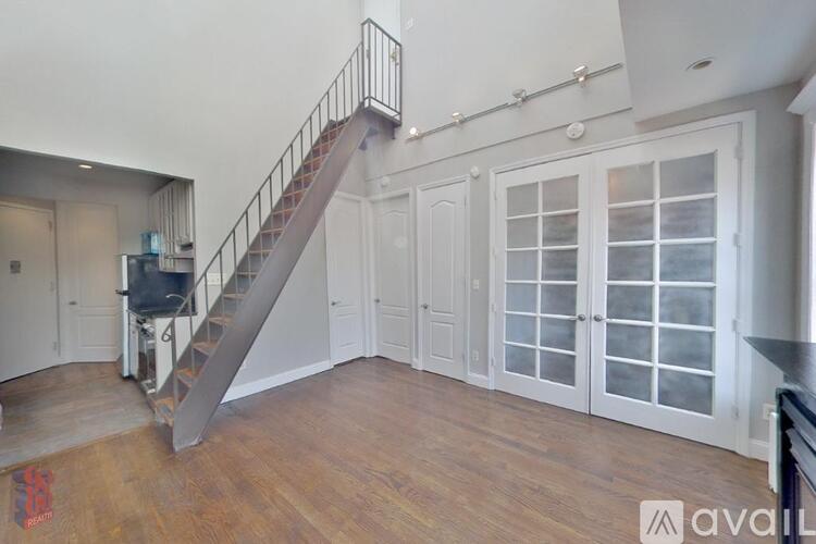 A spacious room with a staircase and a glass door.