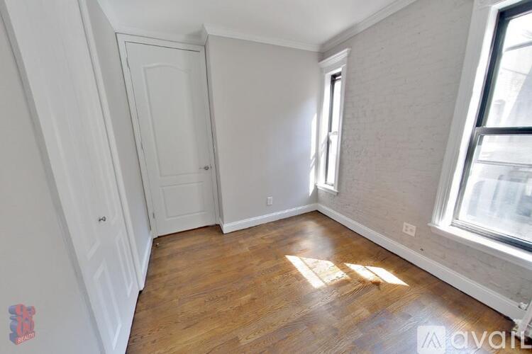 A room with wooden flooring and a window letting in sunlight.