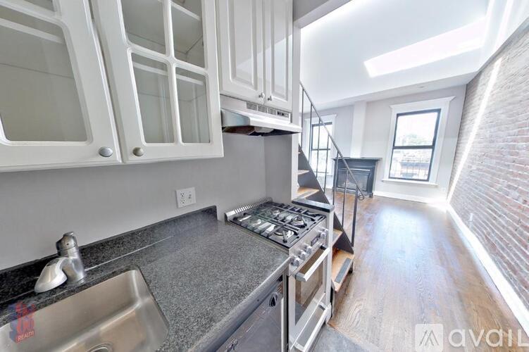 A kitchen with white cabinets and a stainless steel sink.