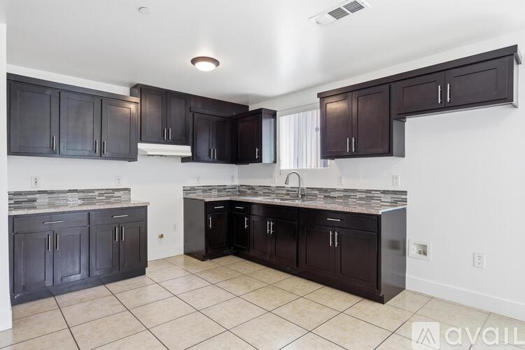 A kitchen with dark brown cabinets and a granite countertop.