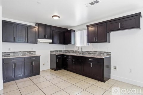 A kitchen with dark brown cabinets and a granite countertop.