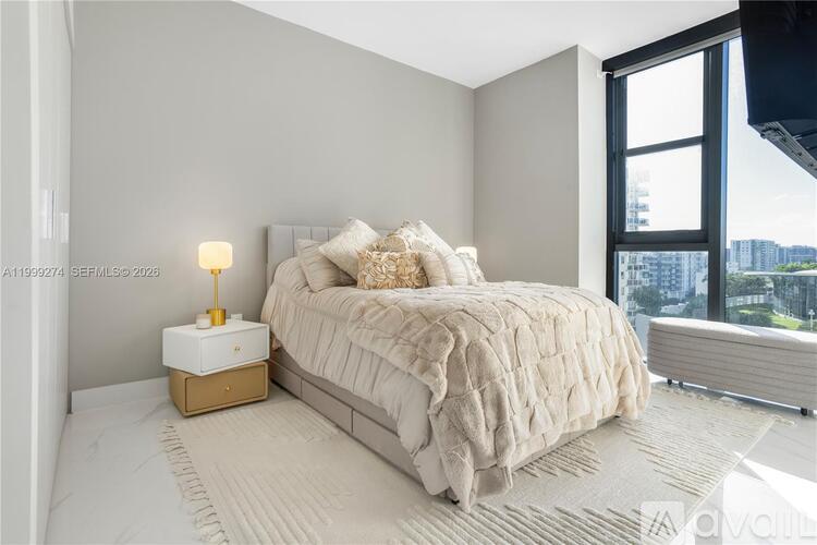 A bedroom with a large bed and a window overlooking a cityscape.