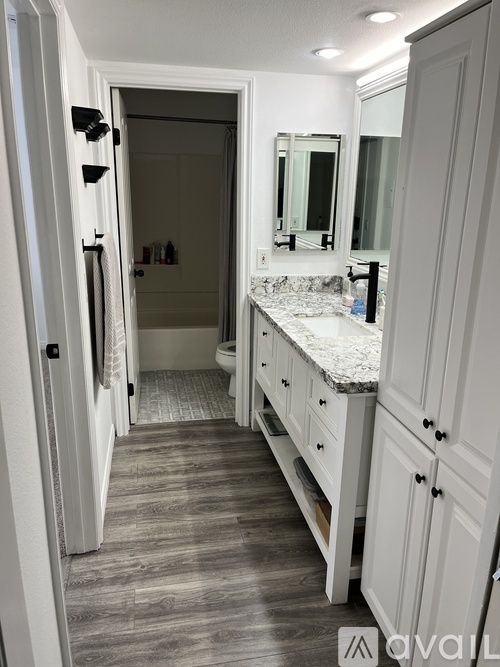 A bathroom with a marble countertop and white cabinets.