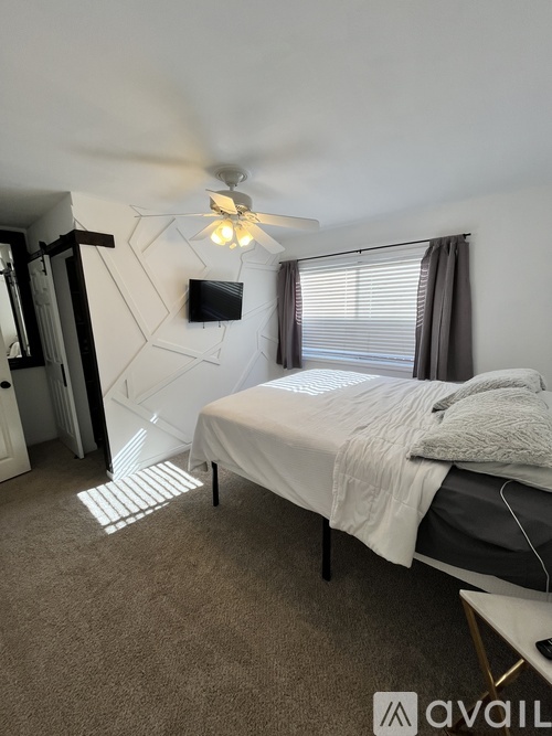 A bedroom with a bed, a ceiling fan, and a television.