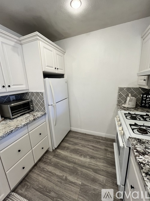A kitchen with white cabinets and a marble countertop.