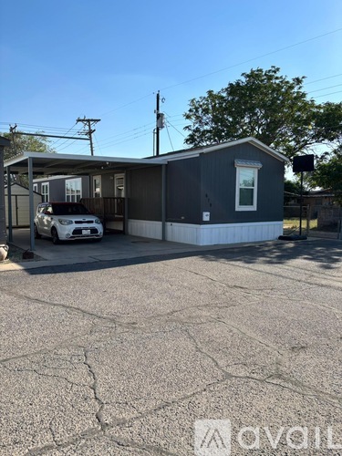A small grey building with a white car parked in front.