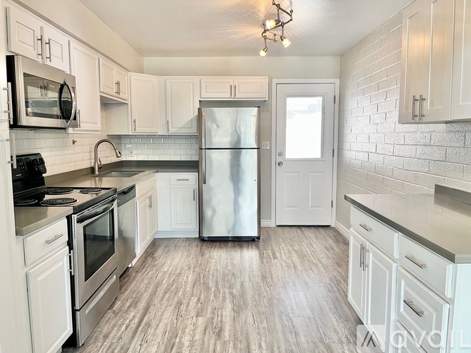 A kitchen with white cabinets and a stainless steel refrigerator.