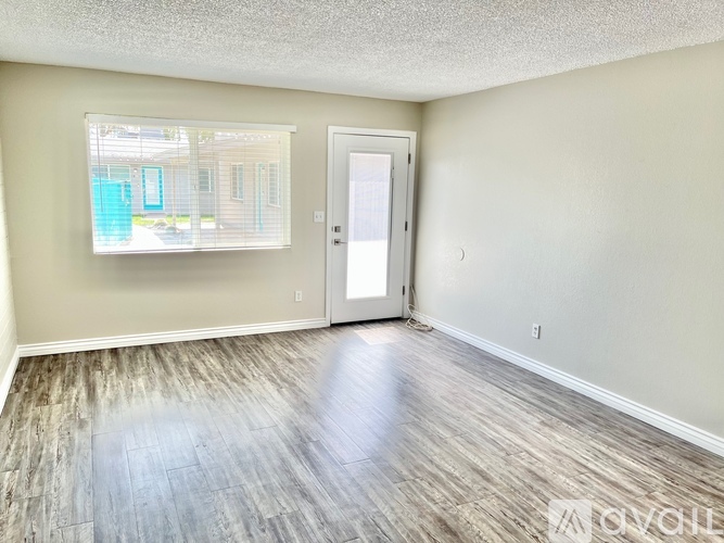 A room with a door and a window with a view of a building outside.