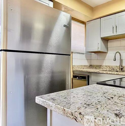 A stainless steel refrigerator in a kitchen with granite countertops.