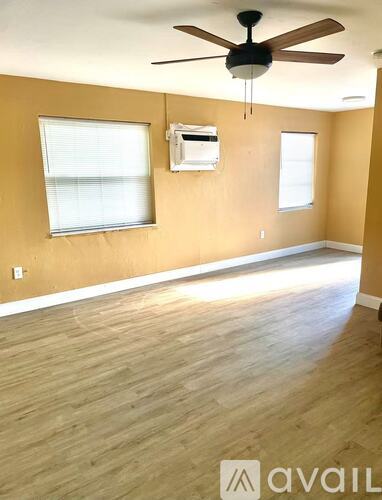 A room with a ceiling fan and two windows.