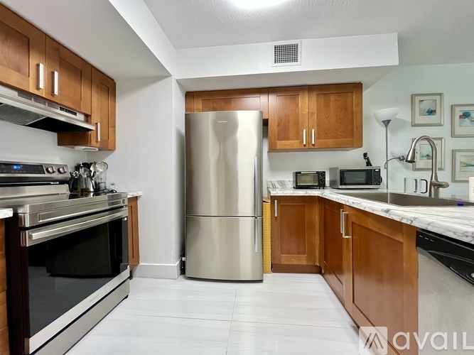 A kitchen with a stainless steel refrigerator and wooden cabinets.