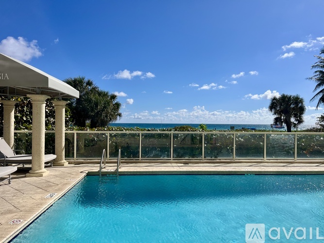 A pool with a view of the ocean and palm trees.