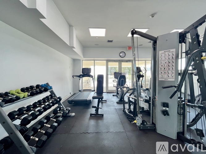 A gym with a variety of equipment including dumbbells, a treadmill, and a weight machine.