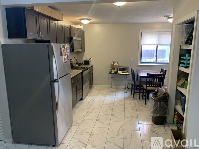 A kitchen with a refrigerator, sink, and dining table.