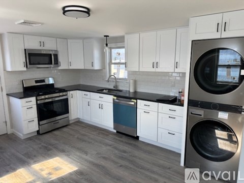 A modern kitchen with white cabinets and a washing machine.