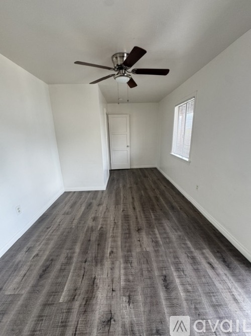 A room with a ceiling fan and wooden flooring.