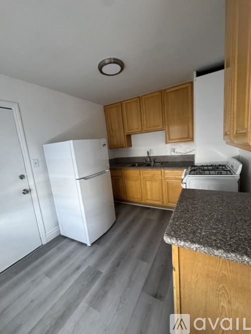 A kitchen with a white fridge, wooden cabinets, and a granite countertop.