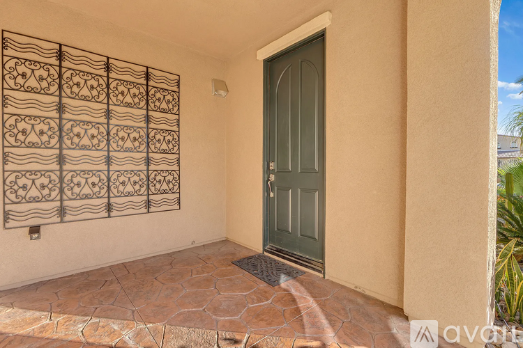 A green door is on the right side of a wall with a decorative iron gate.