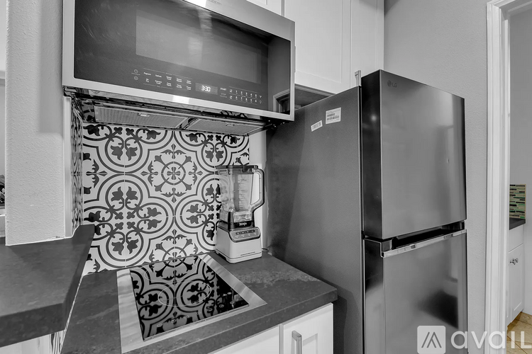 A black and white photo of a kitchen with a refrigerator, microwave, and oven.