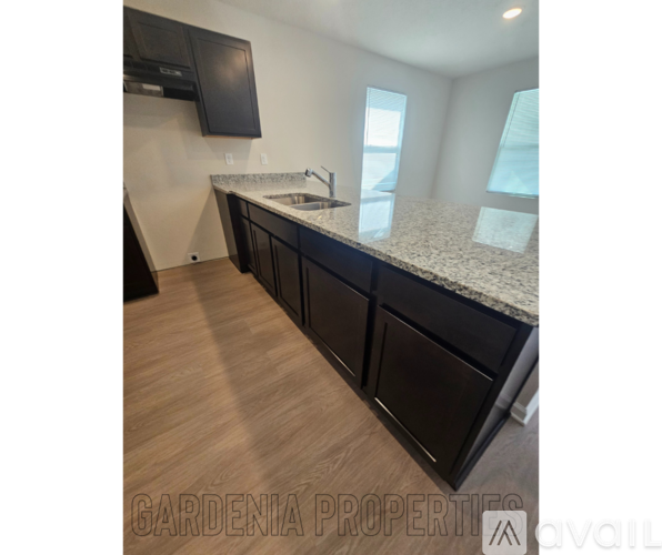 A kitchen with black cabinets and a granite countertop.
