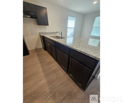A kitchen with black cabinets and a granite countertop.