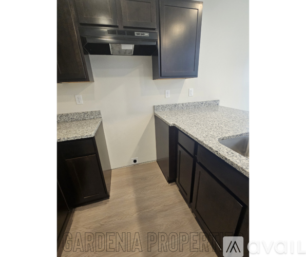 A kitchen with dark brown cabinets and granite countertops.