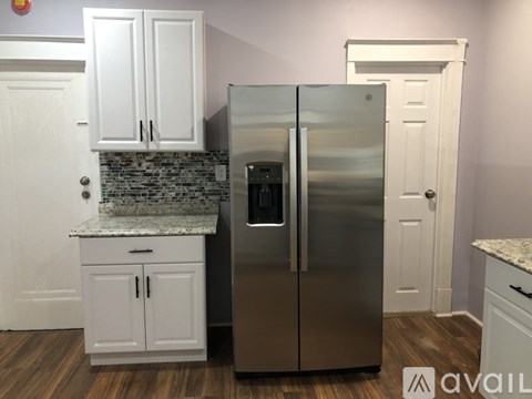 A kitchen with a stainless steel refrigerator and white cabinets.