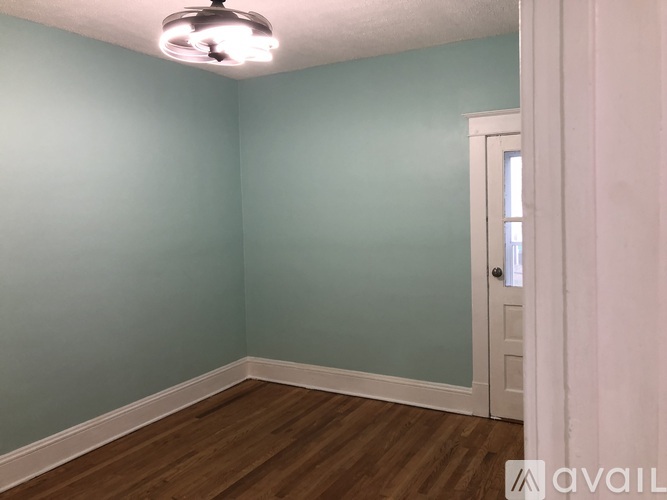 A room with a white door and wooden floor.